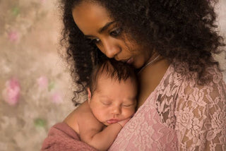 A tender moment between parent and sleeping baby wrapped in soft pink fabric.